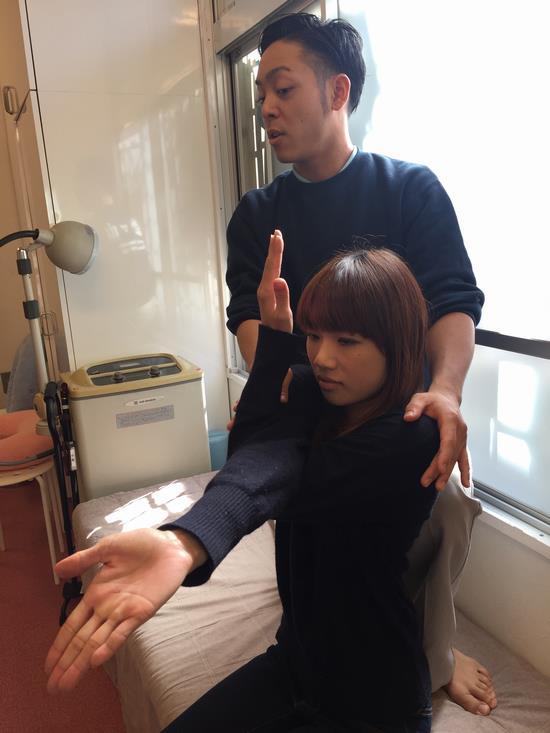 男性が後ろから、女性に手のストレッチをしている写真