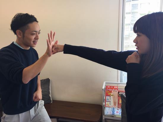 女性が右手のグーで男性の右手にパンチする写真