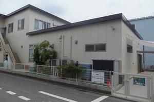 横長の1階建ての隣に2階建てがあり、2階への階段が外にあるくれよん保育室の外観写真