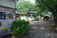 大きな木々が植えられ、ブランコや滑り台なども遊具がある館外（児童遊園）の写真