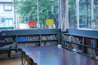 大きな窓と本が詰まった本棚、中央にはテーブルと椅子がある山際児童館図書室の写真