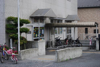 自転車が何台か停めてある、白い建物の児童館外観の写真