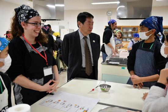 外国人の先生と児童との英語でのやり取りを見守る小林市長の写真