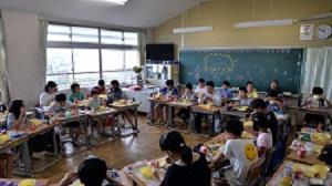 生徒たちが机を大きな円状に並べて給食を食べている写真