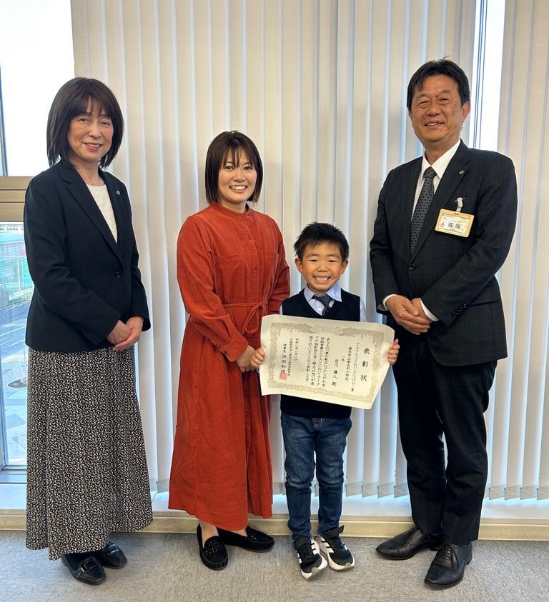 左から、高峰南毛利小学校長、吉川さん保護者、賞状を持つ吉川さん、佐後教育長が記念撮影をしている写真