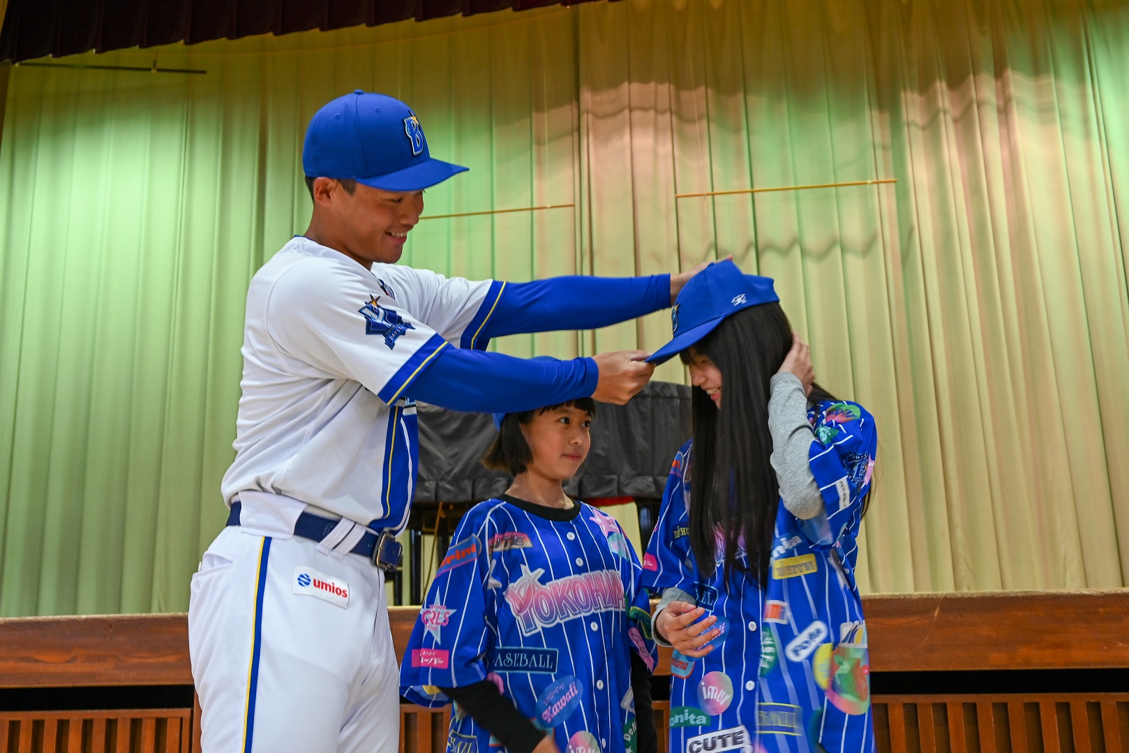 横浜DeNAベイスターズ 加藤響選手が帽子を児童に渡している様子写真