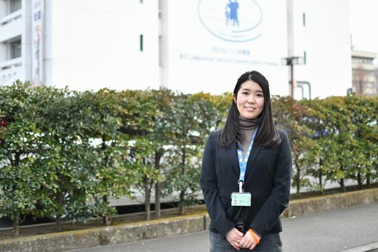 生け垣の前に立っている女性職員の写真