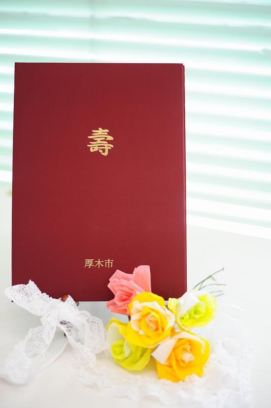 赤地に金色の文字で中央に壽、下に厚木市と記載されている婚姻届記念証の表紙の写真