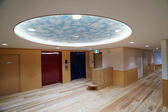 おひさまっこ保育園の室内で、ホールの天井に大きく、青い空を感じる天板がある写真