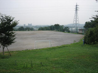 街並みが見渡せる高台に、2つのサッカーゴールがあり、手前に芝生が広がる施設内の写真
