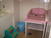 右側にピンク色のおむつ替えのベッドが置いてあり、左側には小さな子供用の踏み台がある洗面台の写真