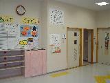 壁に時計や掲示物が掲示されている岡田児童館の館内入口の写真