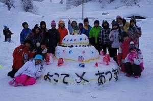 雪で作った、よこて・あつぎと書いたケーキと子供達とで集合写真