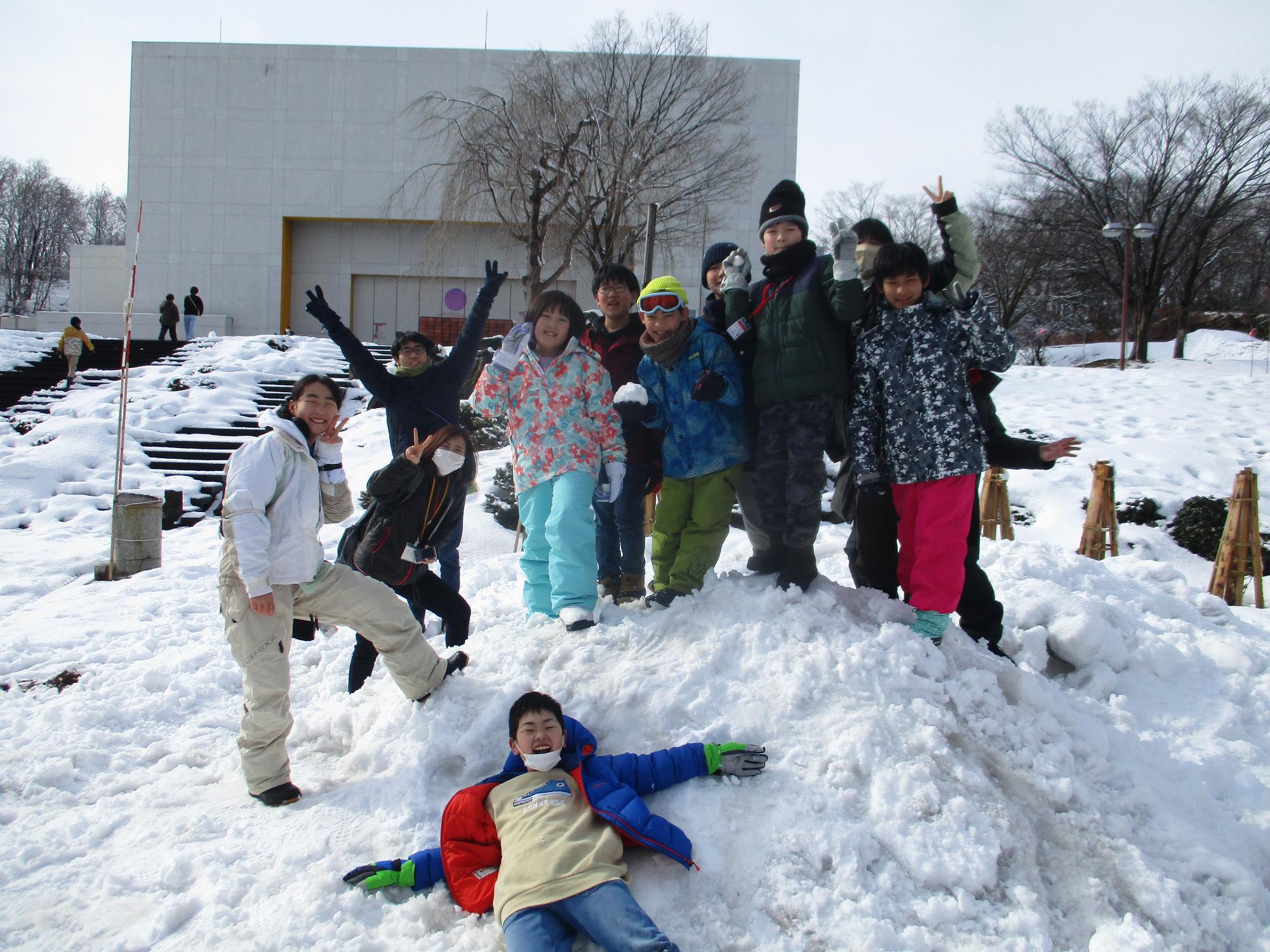 雪で作った、よこて・あつぎと書いたケーキと子供達とで集合写真