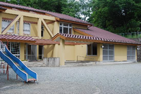 黄色い壁の鳶尾児童館の入口の手前に滑り台が設置されている写真