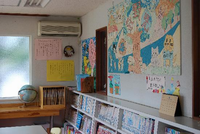壁に掲示物があり、壁際には地球儀やたくさん本の並べられた本棚が設置してある荻野児童館の図書室の写真