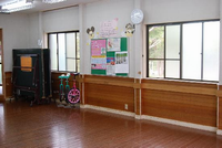 壁際に一輪車や卓球台がなおされており、広々とした木のフローリングの古松台児童館の遊戯室の写真