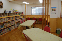 3段の本棚にきれいに本が並べられており、本棚の前には読んだりできるように机といすも用意されている図書館の写真