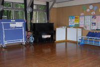 壁際に卓球台や一輪車、ピアノなどが置かれているまつかげ台児童館の遊戯室の写真