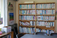 壁際にたくさんの本が並べられた本棚が設置してあります。本棚の前には、テーブルと椅子が並べられている上依知児童館図書室の写真