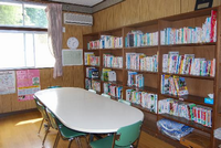 壁際に本棚が設置されており、本棚の前にテーブルと椅子が置かれている館内（図書室）の写真