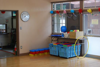 おもちゃやフラフープが置かれてあるフローリングの遊戯室の写真