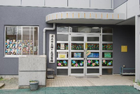 玄関がガラス窓で窓にかわいい装飾が施されている緑ヶ丘児童館の正面写真