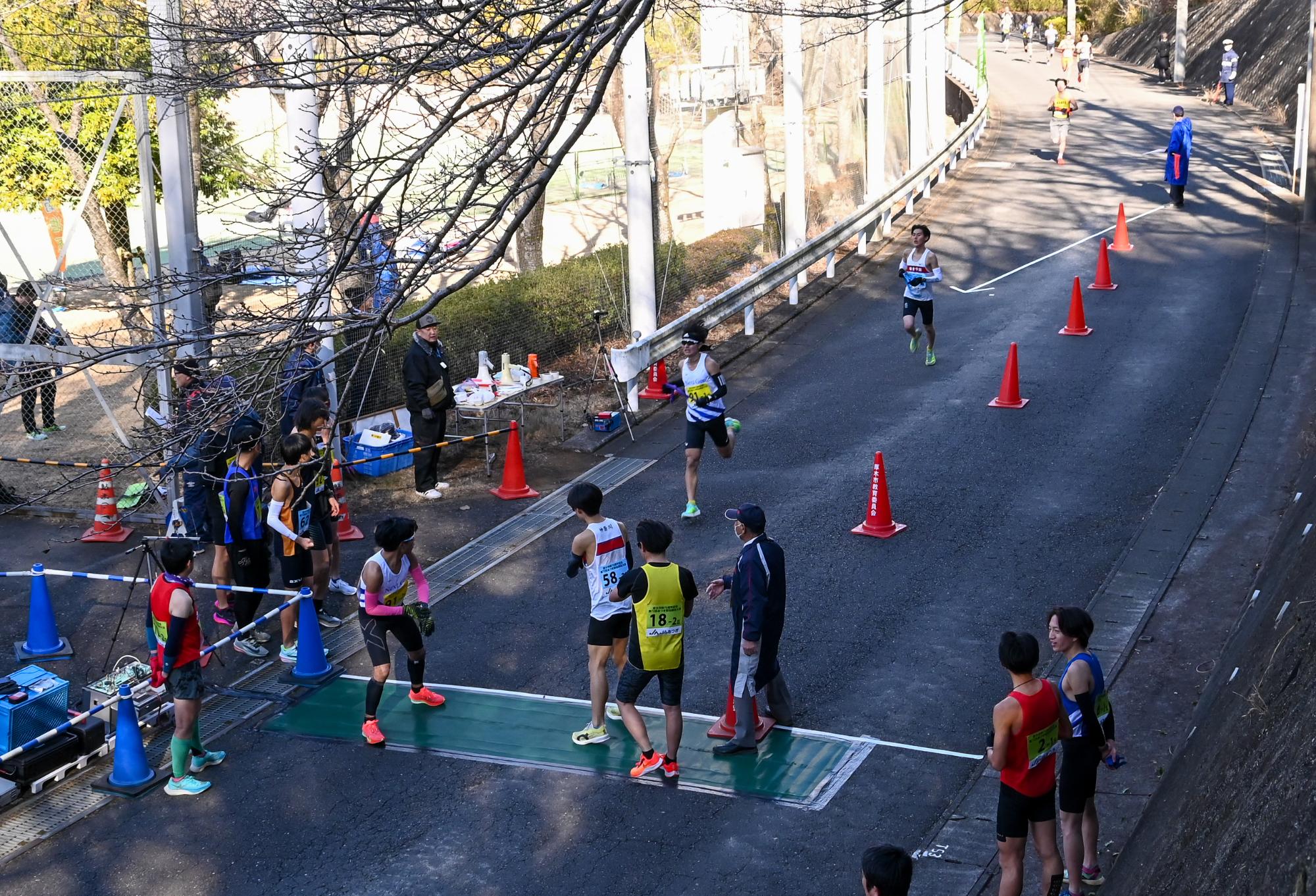 第1中継地点でたすきをつなぐランナーたち