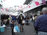 国旗で飾られたテントのイベント会場に人々が賑わっている写真