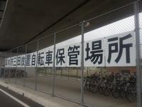 「三田放置自転車保管場所」と書かれたプレートが金網にかかっている写真