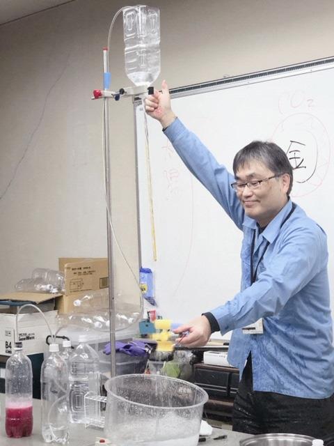 ペットボトルで作られた装置で実験をしている菅原さんの写真