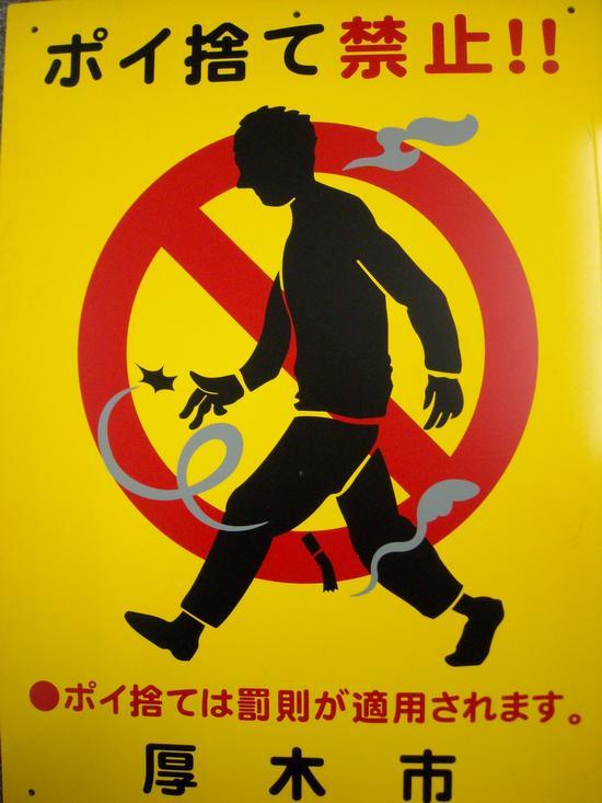 人がたばこの吸殻のポイ捨てをしているイラストに禁止マークが描かれ、「ポイ捨て禁止！！ポイ捨ては罰則が適用されます。厚木市」と文字の書かれた看板