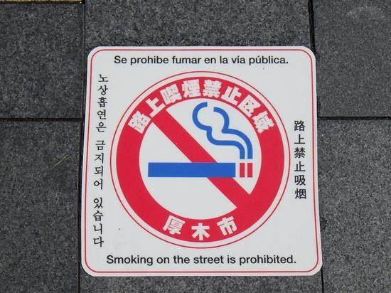 火のついた煙草に赤で禁止を表す斜線が描かれた路上喫煙禁止区域の路面シートのアップ写真
