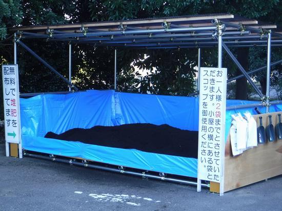青いビニールシートの上に堆肥が置かれて両脇に案内の立て看板が置かれている堆肥配布場所の写真