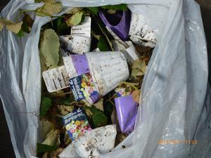 ゴミ袋に入れられた落ち葉と一緒にビニールポットや商品のラベルが入れられてある写真