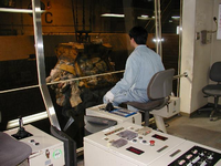 作業服を着た男性がクレーン操作室でごみ処理をしている写真