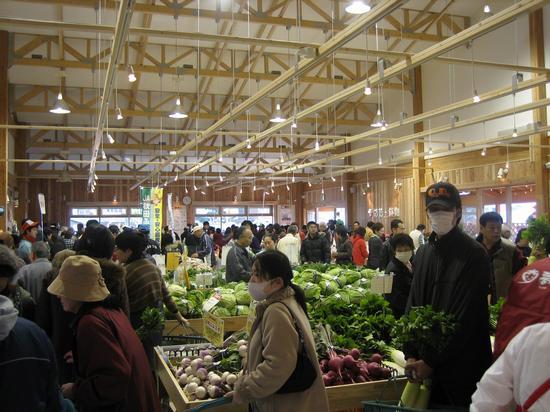 夢未市の店内の中央に沢山の野菜が並べられ、大勢の買い物客が買い物をしている写真