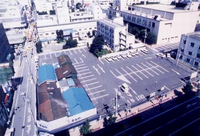 道路沿いの商店街と隣接する広い駐車場の写真