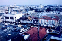 老朽化したトタン屋根などの低層の建物が建ち並ぶ商店街を高台から撮影した写真