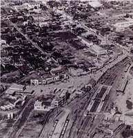 右側縦に線路が通っており駅と思われる周辺に、建物が点在している昭和時代の本厚木駅周辺を上空から撮影した写真