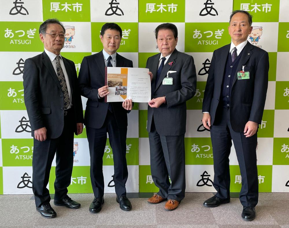 梶田委員長と小林市長が一緒に提言書を持ち、左端に齊藤職務代理、右端に上前副市長が並んでいる写真