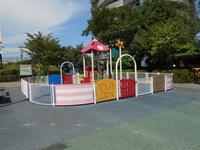 フェンスで囲まれてた中央にピンク色の三角屋根がある幼児用遊具の写真