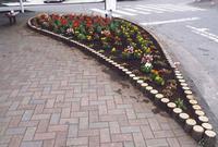 道路脇のレンガで造られた花壇にキレイな花が植えられている写真