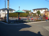 住宅街の一角に、すべり台やベンチ、緑色の屋根の東屋が設置されている長坂北公園の写真