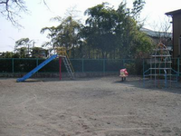 緑色の柵で囲まれた園内奥の左側にすべり台、右側にピンク色のスプリング遊具、その右側にロケットの形をしたジャングルジムなどの遊具が設置されている大六天公園の写真