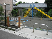 住宅に囲まれた一角にあり、砂場や青と黄色で塗られたすべり台が設置されているひのきやと公園の写真