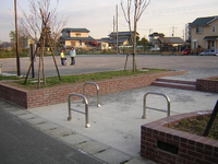 周囲に住宅街があり2つのベンチのみが設置されており中央で親子で遊んでいる、むかいだ公園の写真