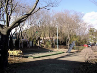周囲に垣根や樹木が点在している園内には、ブランコや砂場、すべり台などの遊具が設置されている愛名第二公園の写真