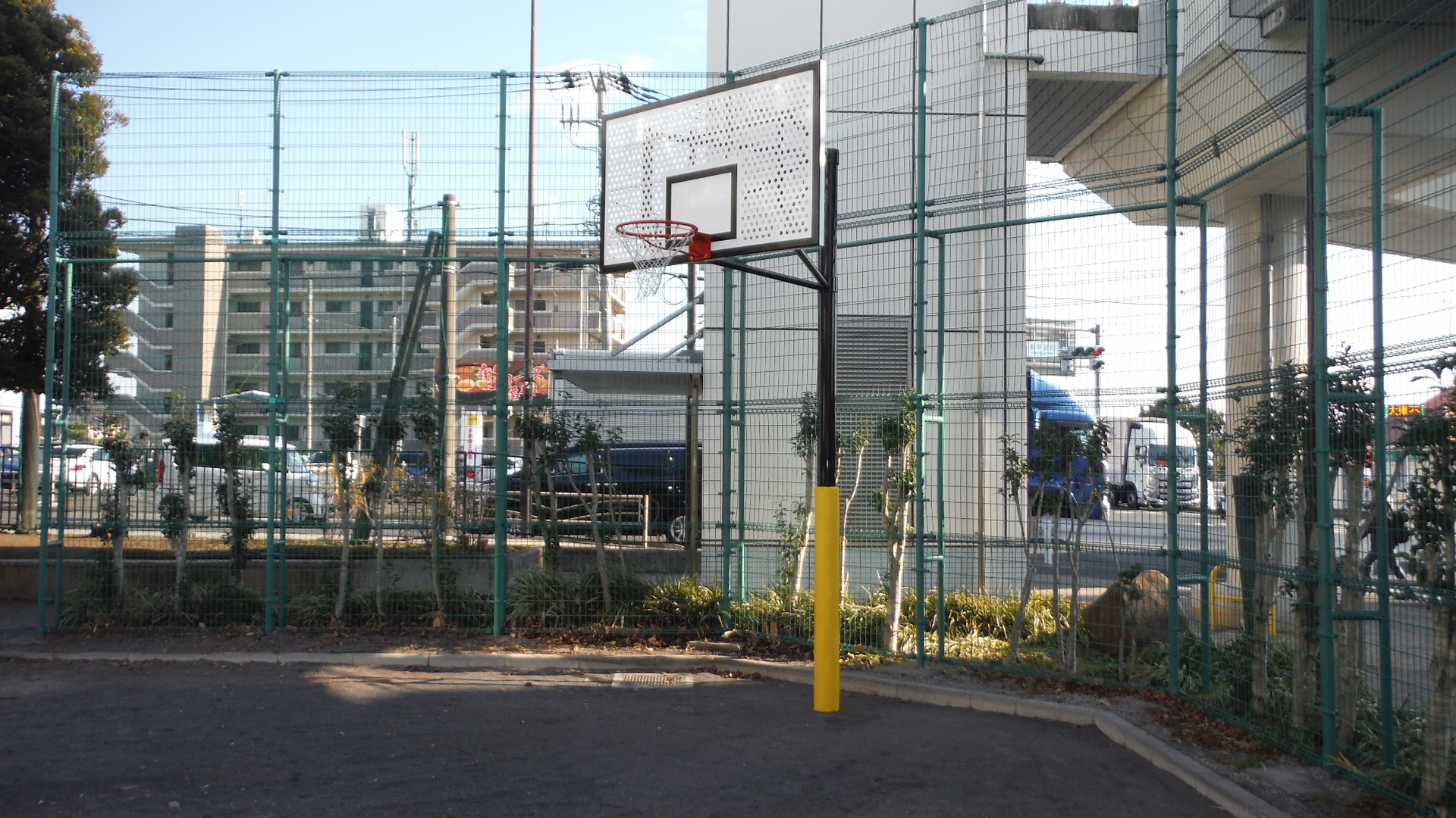歩道橋の階段の左側には広場があり、バスケットゴールが設置されている公園の写真