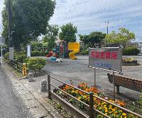 中央の花壇の奥にカラフルな色のすべり台が設置されている公園内の写真